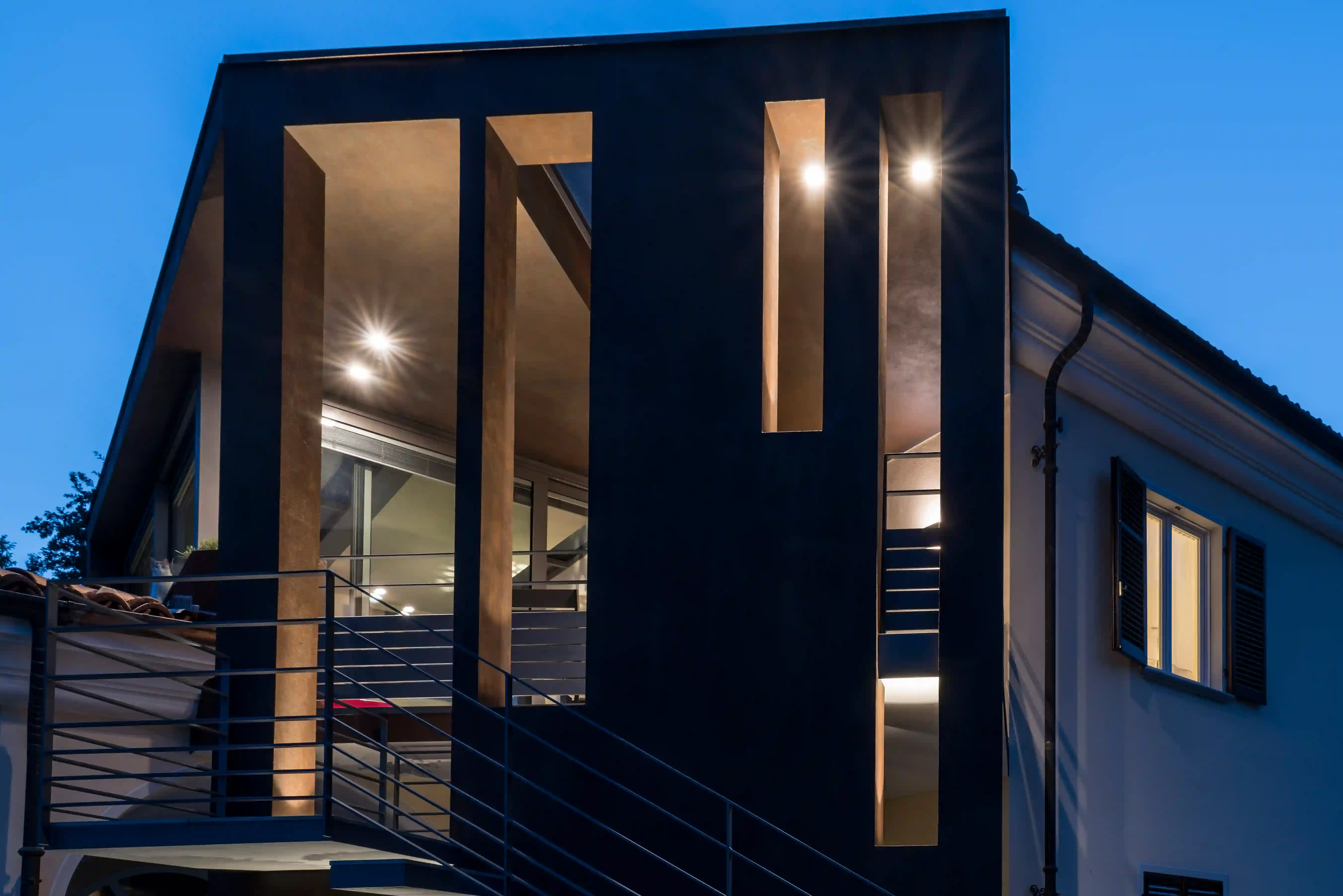 facciata moderna con illuminazione integrata che sottolinea i tagli verticali e i volumi dell'edificio