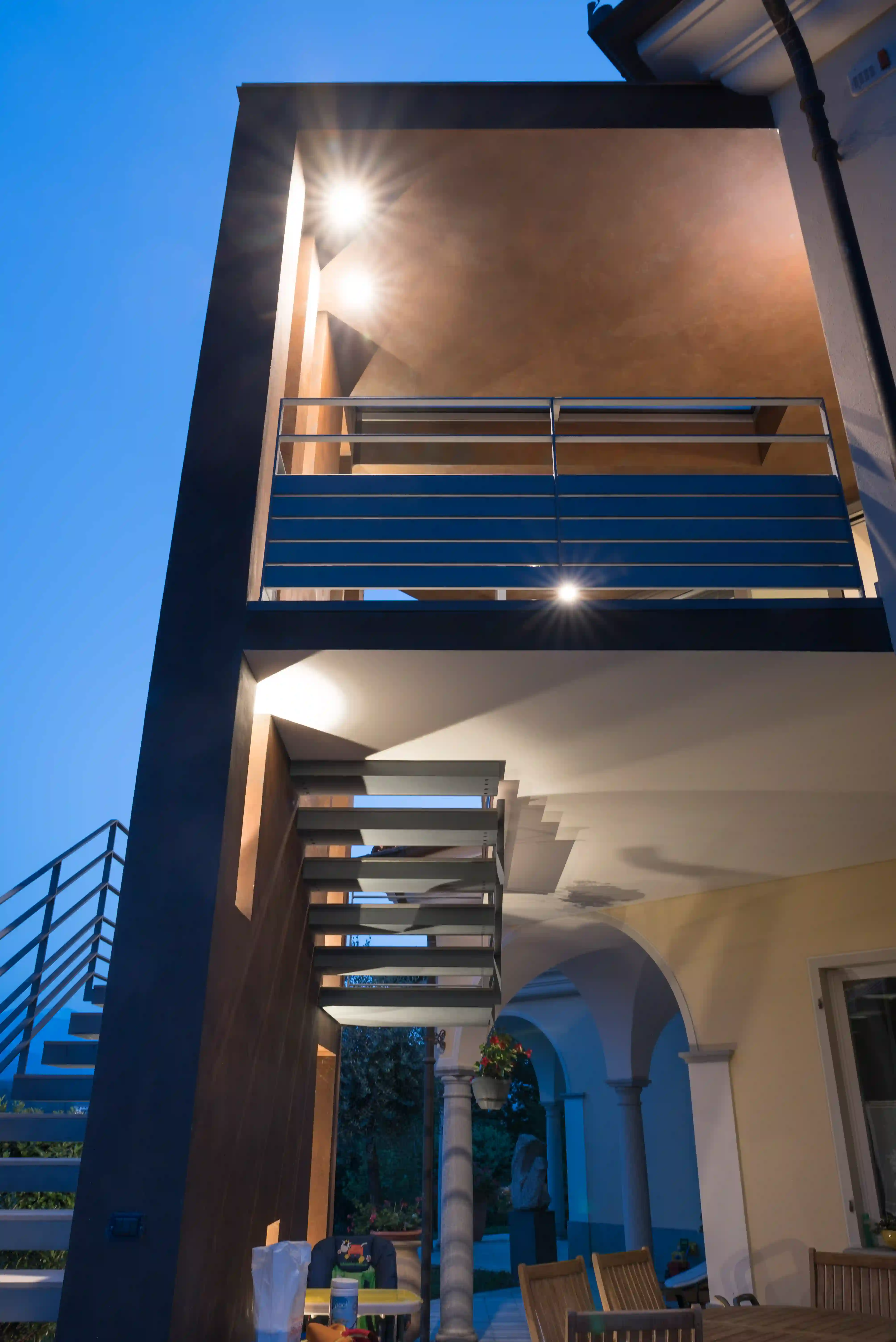 area esterna con dettaglio dei punti luce sotto il volume moderno e scala in metallo illuminata