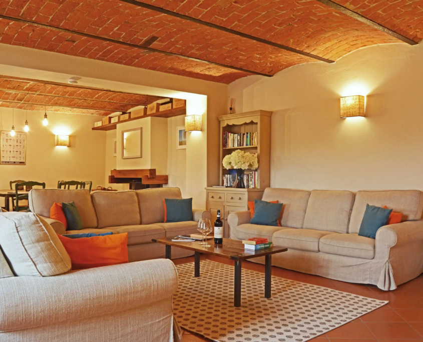 soggiorno rustico con divani beige, soffitto in mattoni e atmosfera accogliente